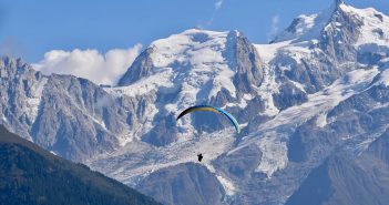 Vacances en Savoie : pourquoi nous sommes séduits Sportif qui fait du parapente au milieu des montagnes enneigées de Savoie